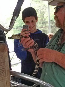 Lucas Jones takes a picture of a small alligator while on the swamp tour.