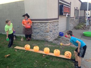 Bert Schnell watches grandchildren Selah Schnell of Pella and Keegan Schnell of Sully try their luck at the pumpkin bean bag game. 