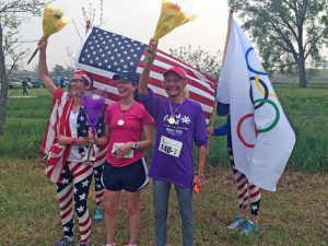 After finishing one of her legs of the race with some runners dressed in Olympic-themed costumers, Bonita Jansen was asked to be part of a photo opp that staged a medal-giving ceremony.