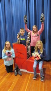 From left: Erika Van Maanen, Ezra Ochsner, Gracie Clayton, and Isabelle Vos hold a few of the shoes and new socks ready for donation